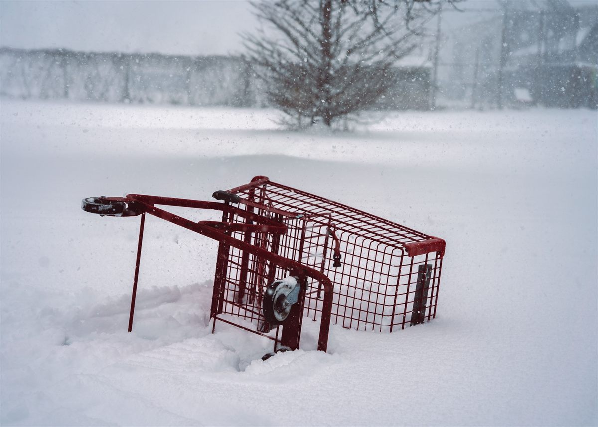 A red shopping cart partly buried in snow.